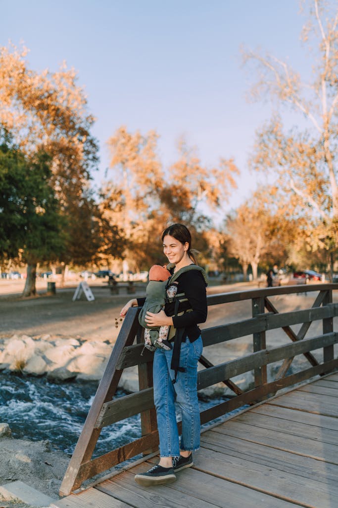 A Woman Standing on a Wooden Bridge while Carrying Her Baby