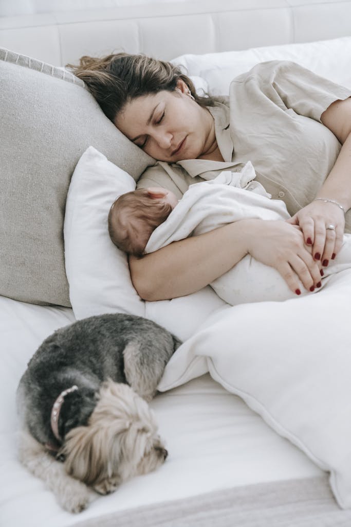 Young mom with cute baby and dog sleeping on bed